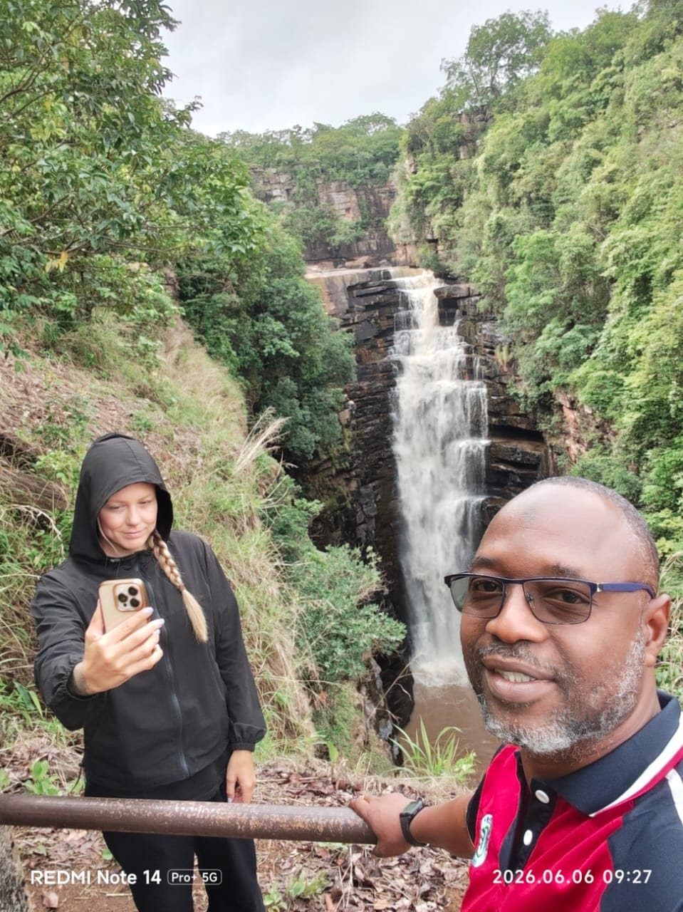 Sylla N'Faly of Guinea Travel and Services with a guest at a waterfall in Guinea